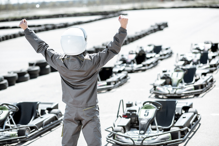 Portrait of a happy racer in protective sportswear standing as a winner of a go-kart race outdoorsの写真素材