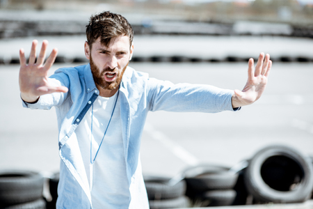 Male instructor showing stop with hands while teaching to park a car on the training ground at the schoolの写真素材