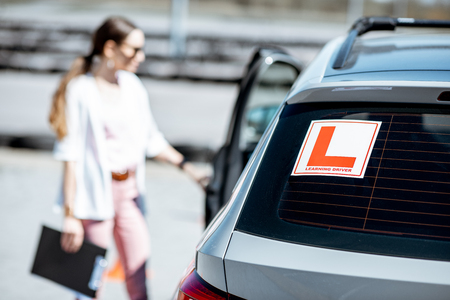 Learning sign on the car with woman driver on the background at the driving school outdoorsの写真素材