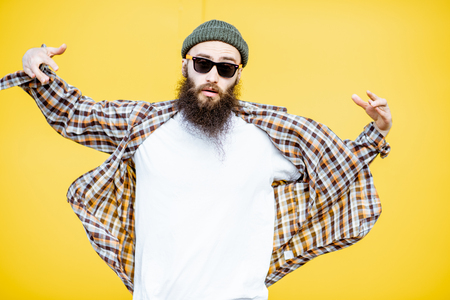 Portrait of a cool stylish man in shirt and hat posing on the bright yellow backgroundの写真素材