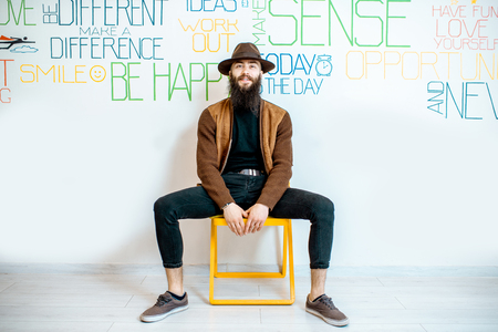 Full body portrait of a stylish bearded man on the wall background with various inscriptions on the topic of mental health indoorsの写真素材