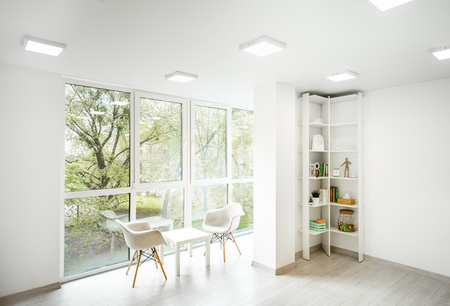 Interior view on the white spacious office with big window, book selves and working place of phychology therapist