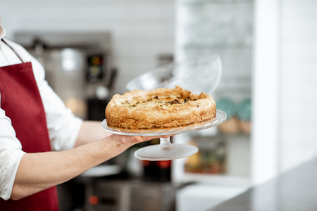 Salesman holding fresh baked pie at the pastry shop, close-up viewの写真素材