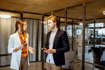 Buiness man and woman having a business convesation standing in the meeting room of the modern officeの写真素材