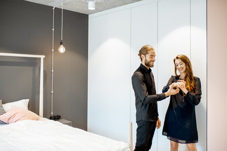 Young couple wearing black formal clothes, preparing for the serious event in the bedroom at homeの写真素材