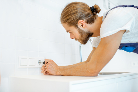 Electrician mounting electric sockets on the kitchen wall at homeの写真素材