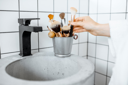 A bucket with makeup brushes on the modern sink in the bathroomの写真素材