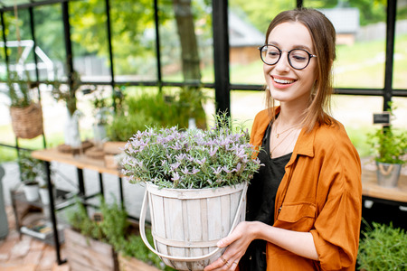 Portrait of a young woman with lavender, taking care of herbs and flowers in the beautiful greenhouse or flower shopの写真素材