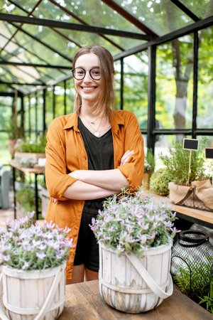 Portrait of a young and confident woman standing as business owner of the beautiful greenhouse or flower shopの写真素材
