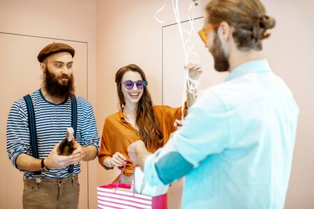 Joyful friends greeting a man with his birthday, giving presents in the apartment hall near the entranceの写真素材