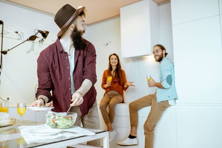 Young friends talking and having some snacks during the meeting on the kitchen at homeの写真素材