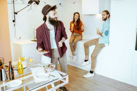 Young friends talking and having some snacks during the meeting on the kitchen at home