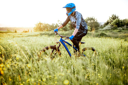 Professional well-equipped cyclist riding on the beautiful green field on the mountains during the...