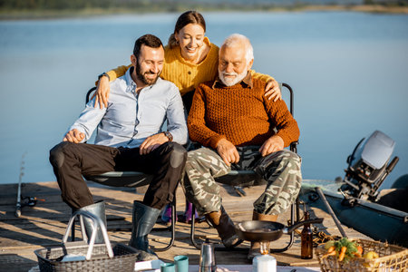 Senior grandfather having warm conversation with his adult son and daughter during the picnic near...