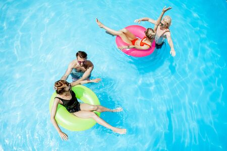 Group of a happy friends having fun, swimming with inflatable toys in the swimming pool outdoors, view from aboveの写真素材