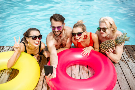 Group of a happy friends making selfie photo with inflatable rings, while having fun on the swimming...