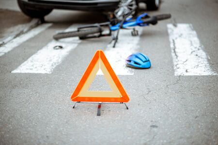 Scene of a road accident with car and broken bicycle lying on the pedestrian crossing. Traffic triangle on the foregroundの写真素材