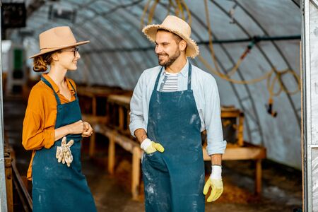 Two well-dressed farmers or agronomists talking together in the hothouse for snails growing on a farmの写真素材