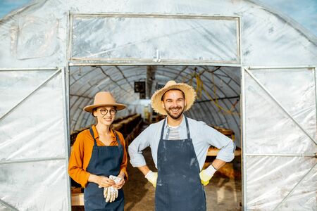 Portrait of a two well-dressed farmers or agronomists standing in front of the hothouse for snails growing on a farm outdoorsの写真素材