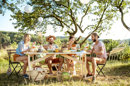 Group of a young friends having festive lunch in the beautifully decorated garden on a summer...