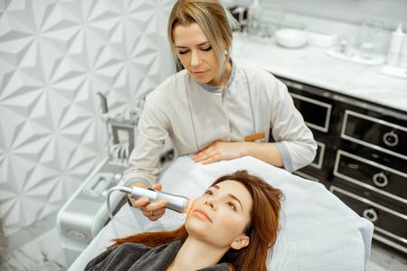 Female cosmetologist making oxygen mesotherapy to a woman at the luxury beauty salon. Concept of a professional facial treatmentの写真素材