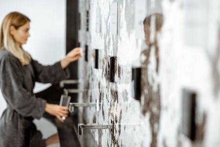 Woman in bathrobe pouring mineral thermal water into the glass at the pump room while resting at the luxury resortの写真素材