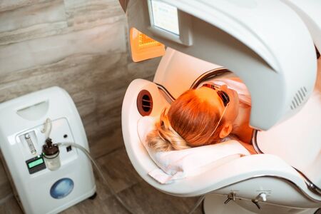 Woman lying in the spa capsule having relaxation, rejuvenation and color therapy in the beauty salonの写真素材