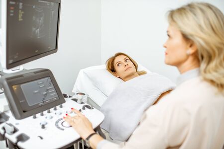 Female doctor performs ultrasound examination of a women's pelvic organs or diagnosing early pregnancy at the medical officeの写真素材