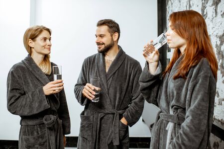 Group of people in bathrobes drinking mineral thermal water at the pump-room while resting at the luxury resortの写真素材