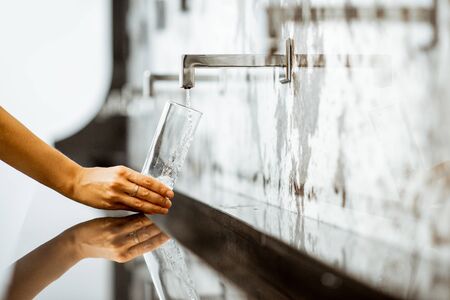 Pouring mineral thermal water into the drinking glass at the pump-room, close-upの写真素材