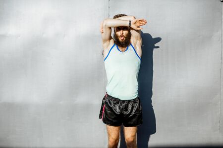Portrait of an energetic, old-fashioned athlete dressed in 80s style posing on the gray wall backgroundの写真素材