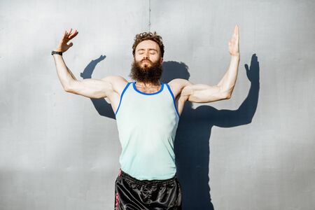 Portrait of an energetic, old-fashioned athlete dressed in 80s style posing on the gray wall backgroundの写真素材