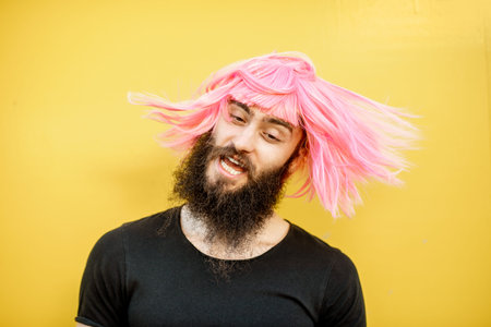 Funny portrait of a stylish playful man with beard and long color hair with expressive emotions on...