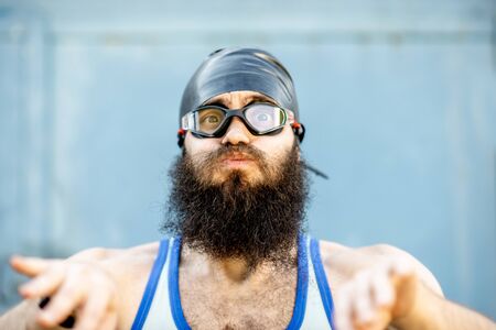 Portrait of a weird, old-fashioned swimmer dressed in 80s style with hat and swimming glasses on the yellow backgroundの写真素材