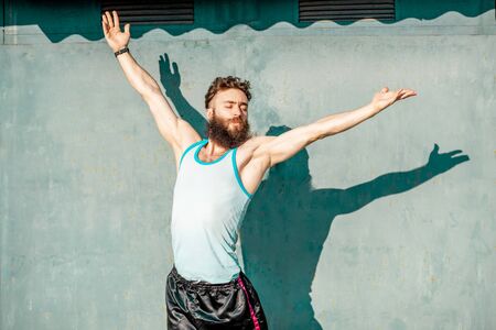 Portrait of an energetic, old-fashioned athlete dressed in 80s style exercising on the green rusty backgroundの写真素材