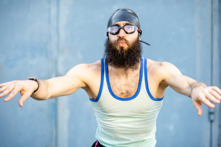 Portrait of a weird, old-fashioned swimmer dressed in 80s style with hat and swimming glasses on the yellow backgroundの写真素材