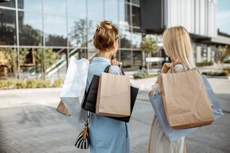 Two women holding empty shopping bags with copy space, while standing back near the shopping mallの写真素材