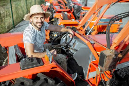 Young agronomist trying tractor for farming, choosing agricultural machinery on the open ground of the shopの写真素材