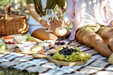Couple having romantic breakfast outdoors, close-up view on the picnic blanket with lots of tasty foodの写真素材