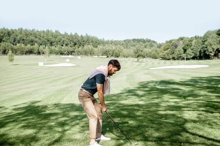 Man playing golf, swinging with putter on a beautiful course on a sunny dayの写真素材