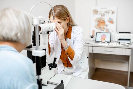 Ophthalmologist examining eyes of a senior patient using microscope during a medical examination in the ophthalmologic officeの写真素材