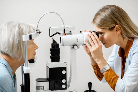 Ophthalmologist examining eyes of a senior patient using microscope during a medical examination in the ophthalmologic officeの写真素材