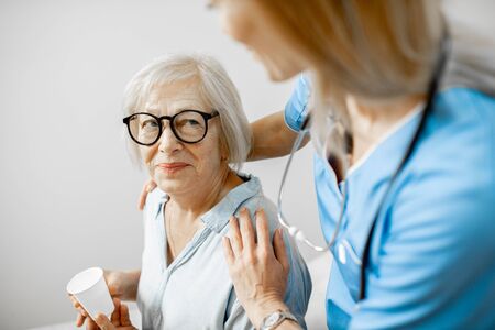 Nurse taking care of senior woman, hugging her shoulders in the clinic or home for elderlyの写真素材