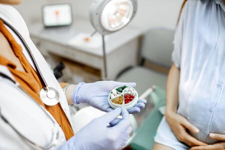 Doctor holding pillbox with some medicine in the gynecological office, close-up view on the hands and pillsの写真素材