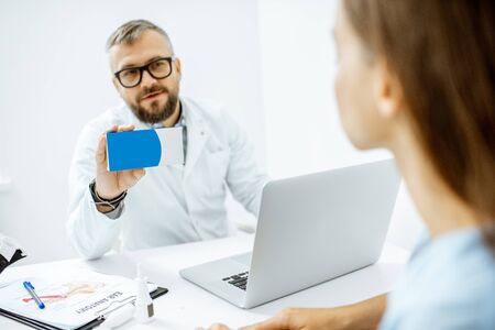 Senior doctor offering some medicine for a young patient, holding box with blank space to copy paste in the medical officeの写真素材