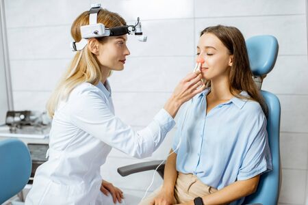Female otolaryngologist making physiotherapy procedure for the nose of a young patient at the ENT officeの写真素材