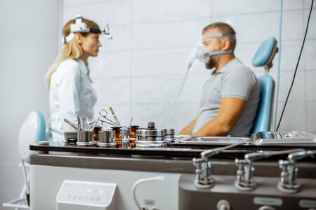 Adult man during a medical breathing treatment with respiratory mask against snoring sitting with doctor at the ENT officeの写真素材