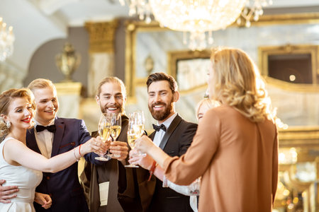 Group of elegant people well-dressed in retro styles hanging out together, having fun with drinks at...