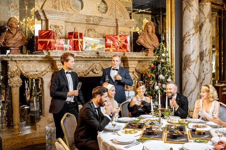 Elegantly dressed group of people having a festive dinner at a well-served table near the fireplace...