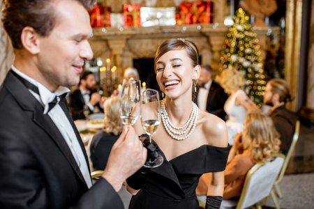 Beautiful well-dressed couple celebrating New Year holiday, standing together with sparcle wine at...